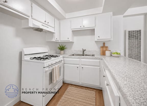 A kitchen with white cabinets and a white stove top oven.