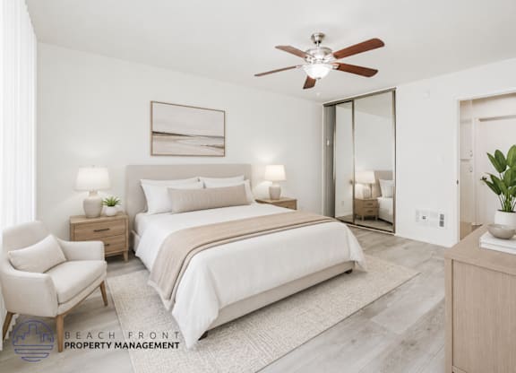 A well-lit bedroom with a large bed, a chair, and a ceiling fan.