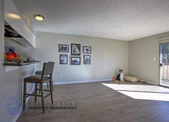 A room with a chair, a dog, and pictures on the wall.