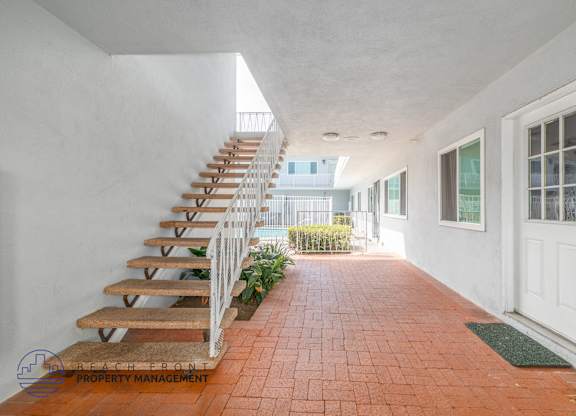 A long hallway with a staircase on the left and a door on the right.