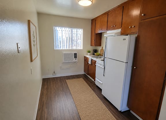 A kitchen with a white refrigerator and wooden cabinets.