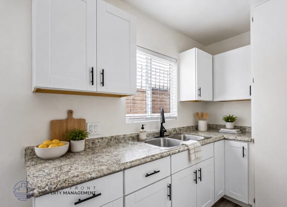 A kitchen with white cabinets and a granite countertop.