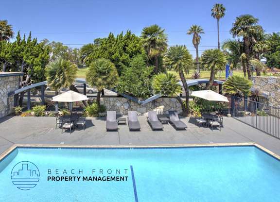 A pool surrounded by palm trees and lounge chairs with the words