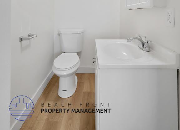 A white bathroom with a toilet, sink, and mirror.