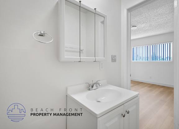 A white bathroom with a sink and mirror.