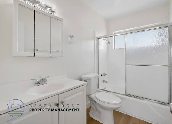 A white bathroom with a sink, toilet, and mirror.