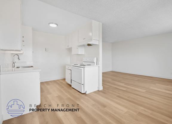 A kitchen with white appliances and wooden floors.