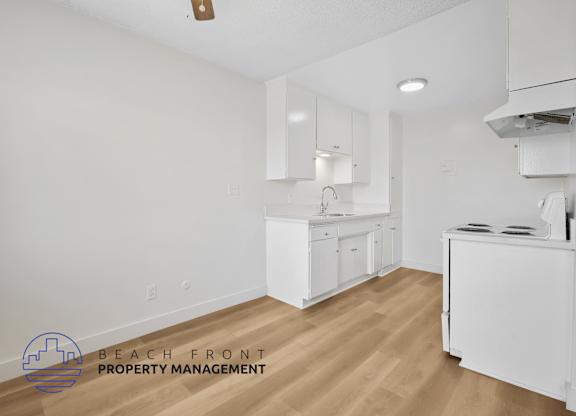 A kitchen with white cabinets and a wooden floor.