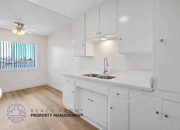 A kitchen with white cabinets and a wooden floor.