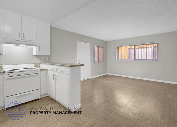 A kitchen with white cabinets and a wooden floor.