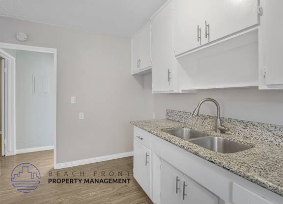 A kitchen with white cabinets and a granite countertop.