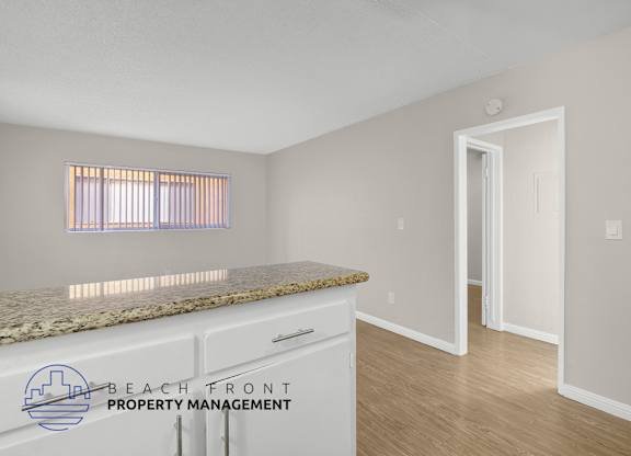 A kitchen with a granite countertop and a window with blinds.