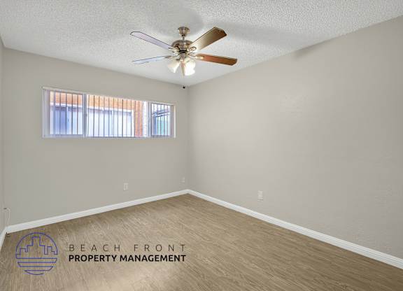 A room with a ceiling fan and a window with blinds.