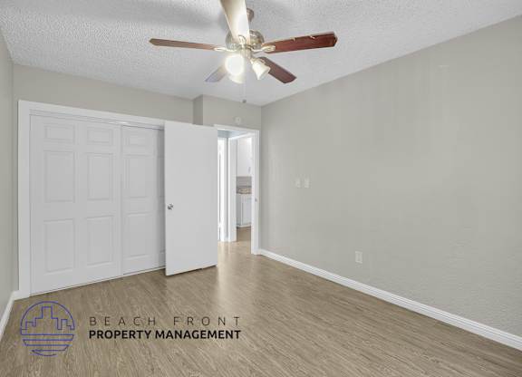 A room with a ceiling fan and a logo for Beach Front Property Management.