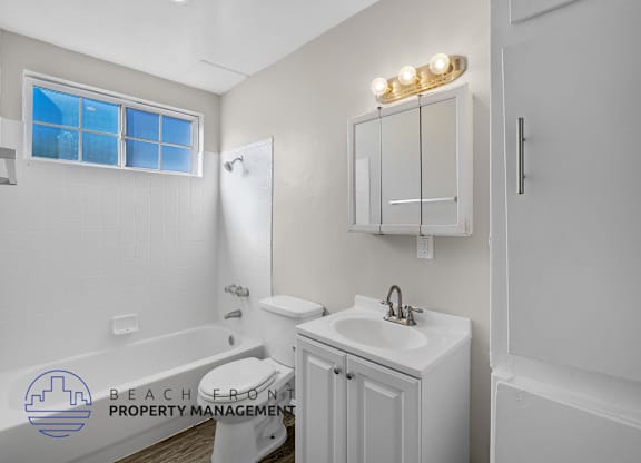A white bathroom with a toilet, sink, and a window.