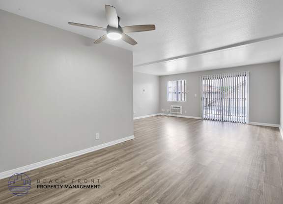 A spacious room with a ceiling fan and wooden flooring.