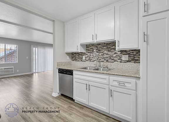A kitchen with white cabinets and a stone backsplash.