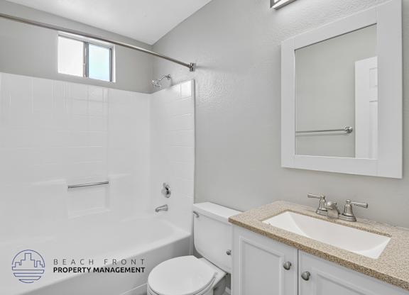 A white bathroom with a toilet, sink, and shower.