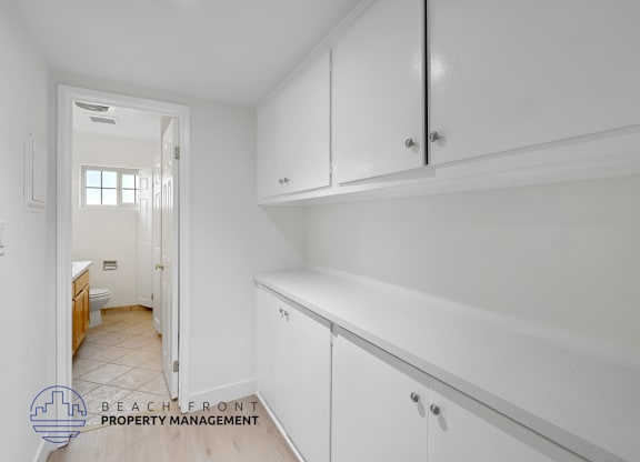 A white kitchen with a logo for Beachfront Property Management.