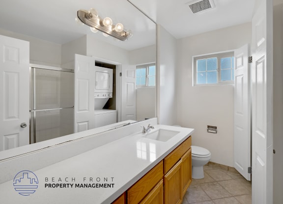 A bathroom with a sink, toilet, and mirror.
