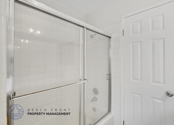 A white door is next to a glass shower stall.