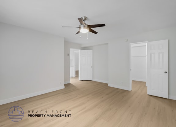 A spacious room with a ceiling fan and wooden flooring.