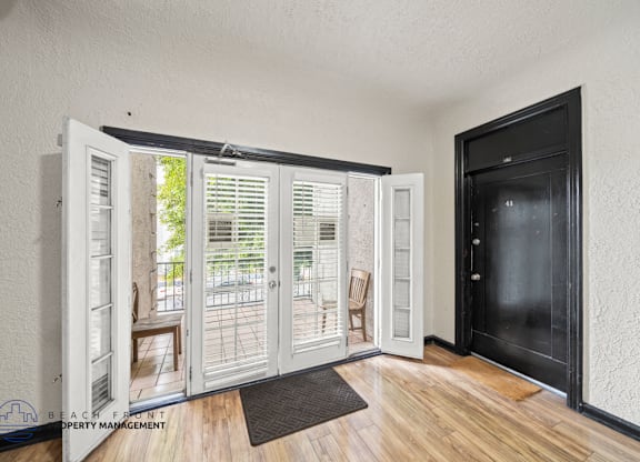 A room with a black door and a wooden floor.