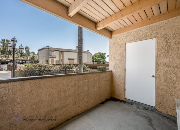 A balcony with a white door and a wall with a logo for Black Iron Property Management.