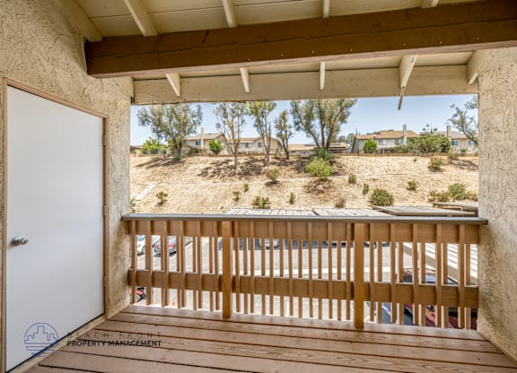 A balcony with a wooden railing and a white door.