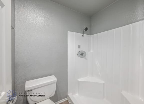 A white bathroom with a toilet, sink, and shower.