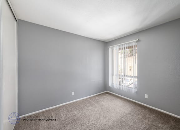 A room with grey walls and a window with blinds.