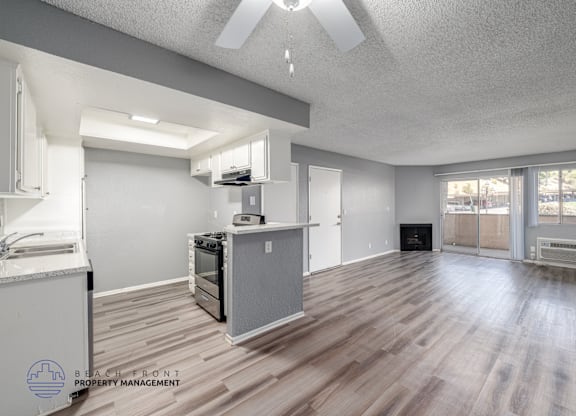 A spacious living room with a kitchen area and a fireplace.