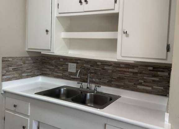A kitchen with white cabinets and a stone backsplash.