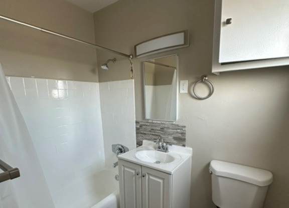 A white toilet sits next to a white sink in a small bathroom.