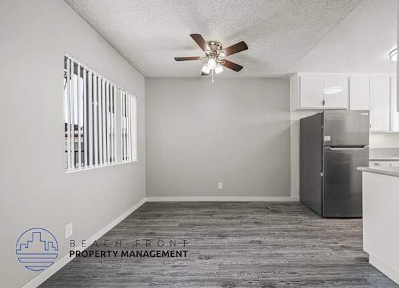 A spacious kitchen and living room with a ceiling fan and wooden flooring.