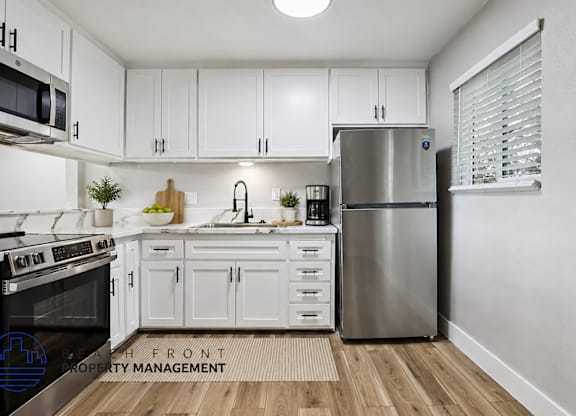 A modern kitchen with white cabinets and stainless steel appliances.