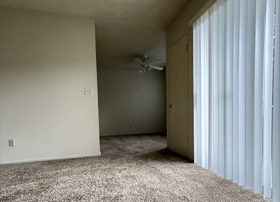 A room with a carpeted floor and a window with blinds.