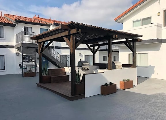 A wooden pergola is in the middle of a patio.
