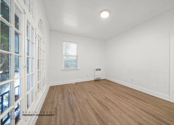 A room with wooden flooring and white walls.