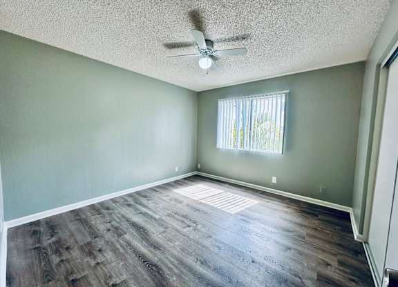 A room with a ceiling fan and a window with blinds.