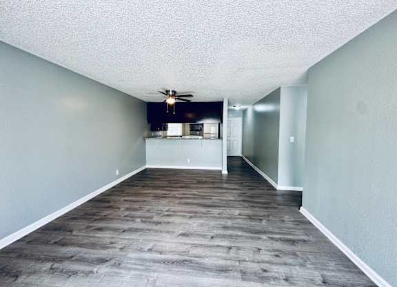 A room with a ceiling fan and a doorway leading to another room.