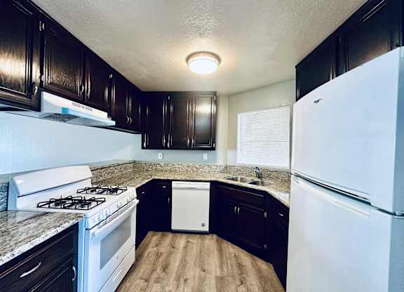 A kitchen with a white fridge and a white dishwasher.