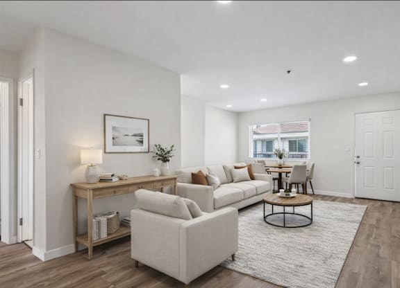 A living room with a white couch, a coffee table, and a television.