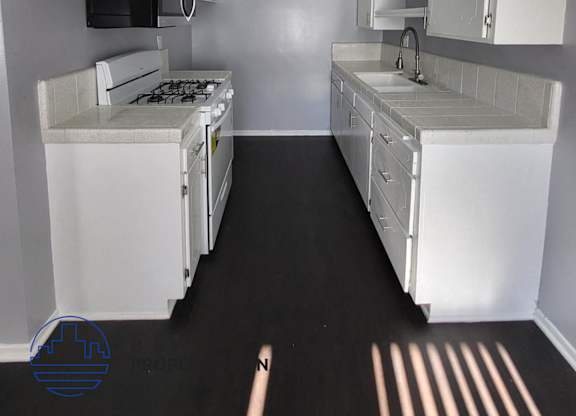 a kitchen with white cabinets and a stove and a sink