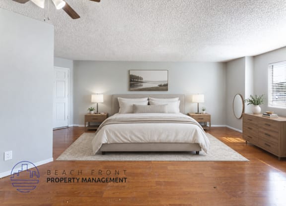 A bedroom with a large bed, two nightstands, and a ceiling fan.