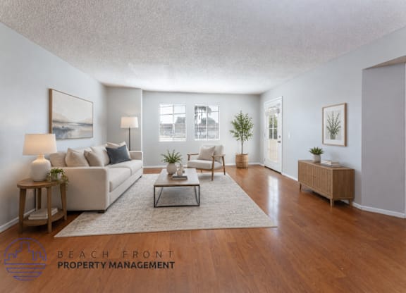 A well-lit living room with a couch, coffee table, and a plant.