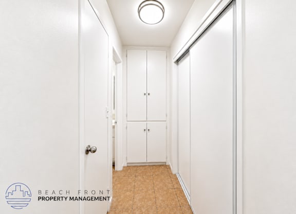 A hallway with a door on the left and a closet with a door on the right.