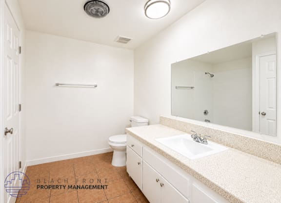 A bathroom with a toilet, sink, and mirror.