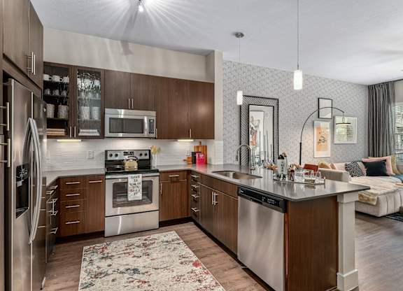 A modern kitchen with dark wood cabinets and stainless steel appliances.