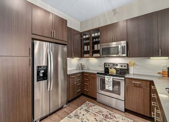 A kitchen with a refrigerator, oven, and microwave.